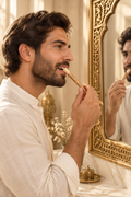 Homme utilisant un siwak épais devant un miroir oriental