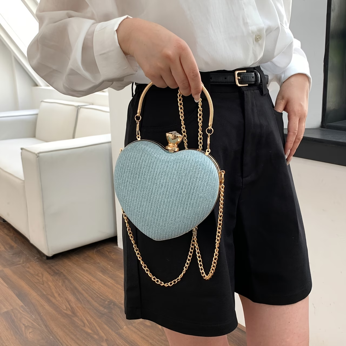 Sac en cœur bleu clair porté à la main, avec anse et chaîne dorées