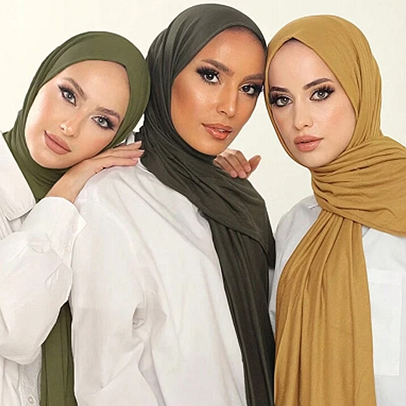 Présentation de foulards unis vert olive, kaki foncé et moutarde portés avec des chemises blanches
